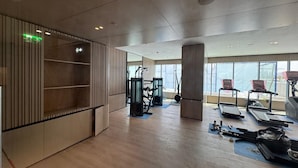 Et moderne fitnesscenter med træningsudstyr, store vinduer og trægulv.