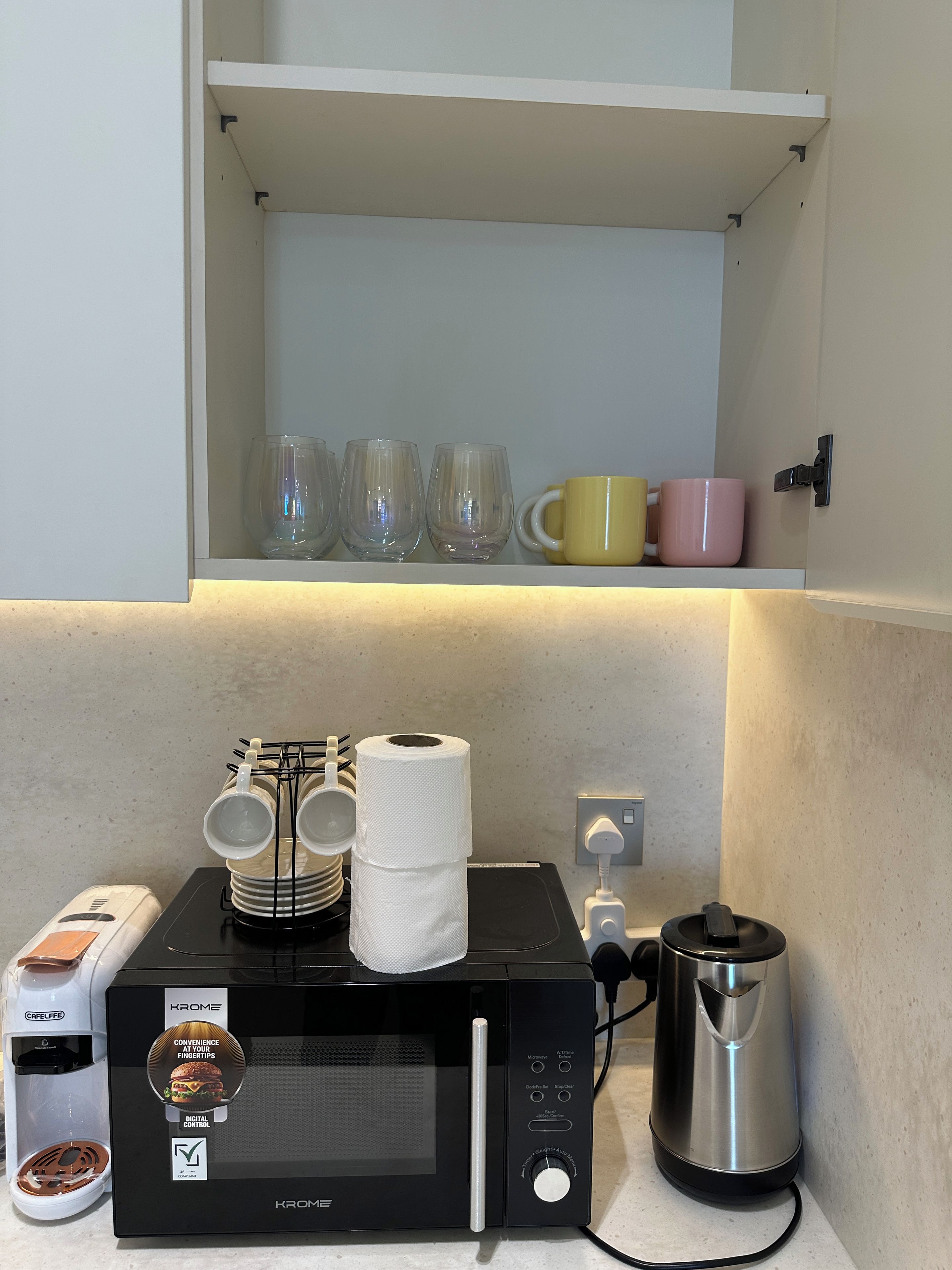 A kitchen area with a microwave, coffee maker, and a kettle.