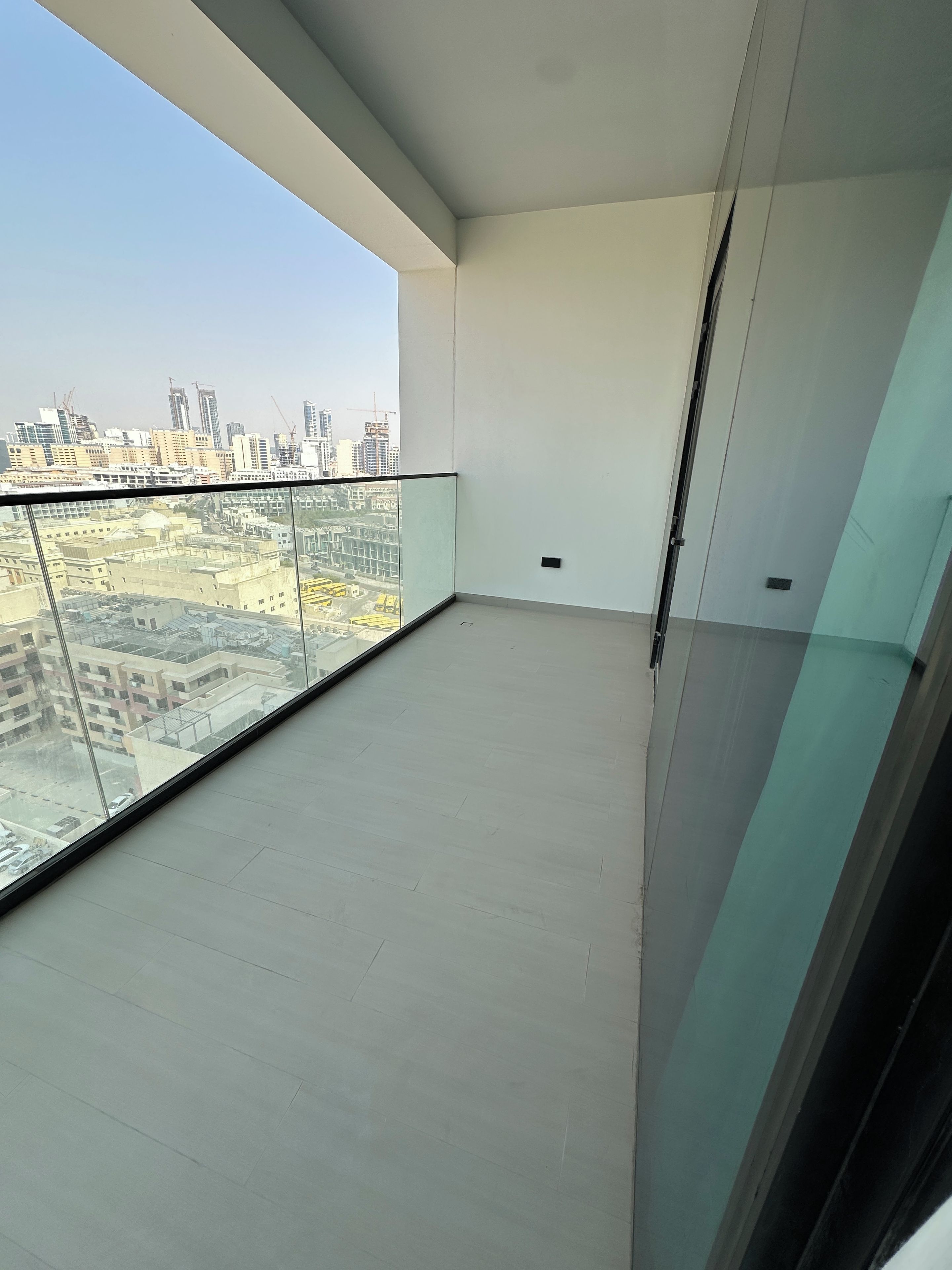 A balcony with a clear view of a cityscape, including buildings and construction cranes.