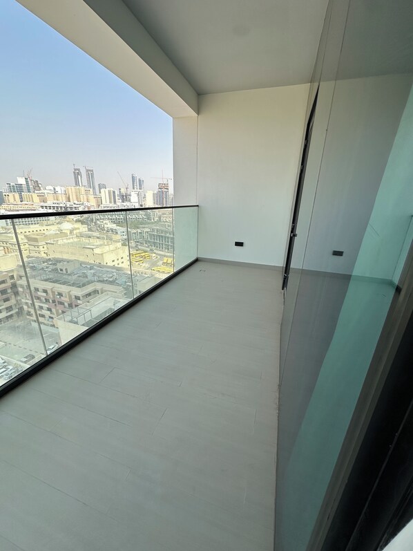 A balcony with a clear view of a cityscape, including buildings and construction cranes.