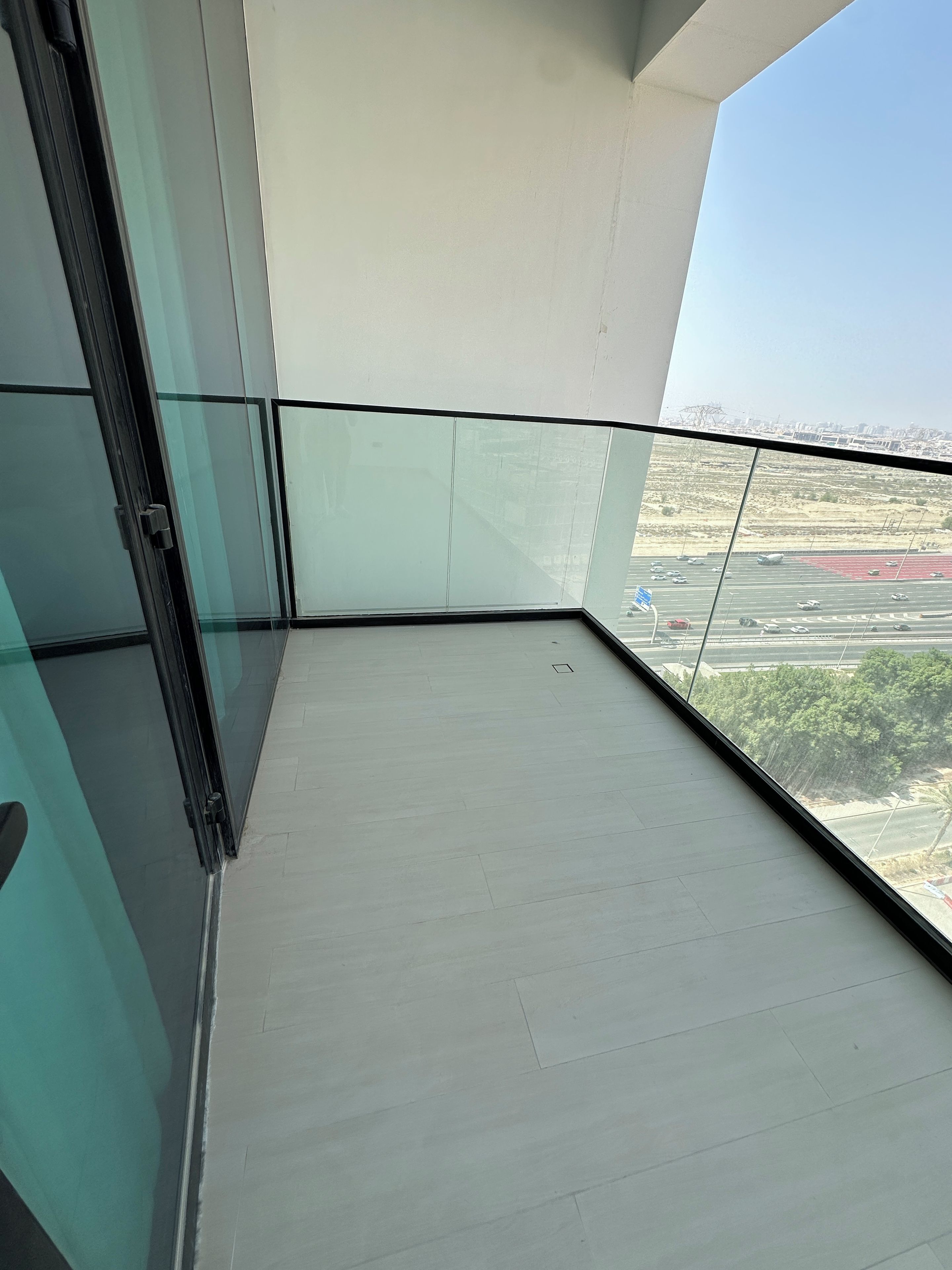 A balcony with a clear view of a parking lot and distant buildings.