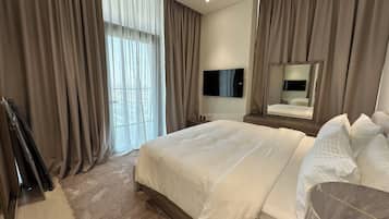 Une chambre d’hôtel avec un grand lit, un téléviseur à écran plat, un miroir et une fenêtre avec des rideaux.