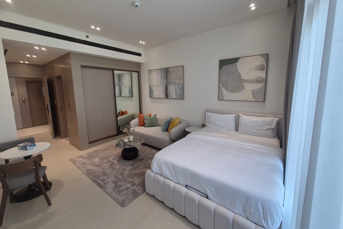 A modern hotel room with a bed, seating area, and a small table.