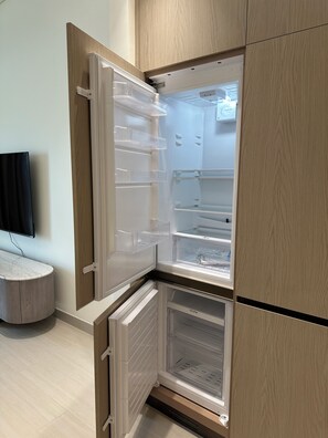 Una cocina moderna con refrigerador empotrado, una encimera y un televisor montado en la pared.