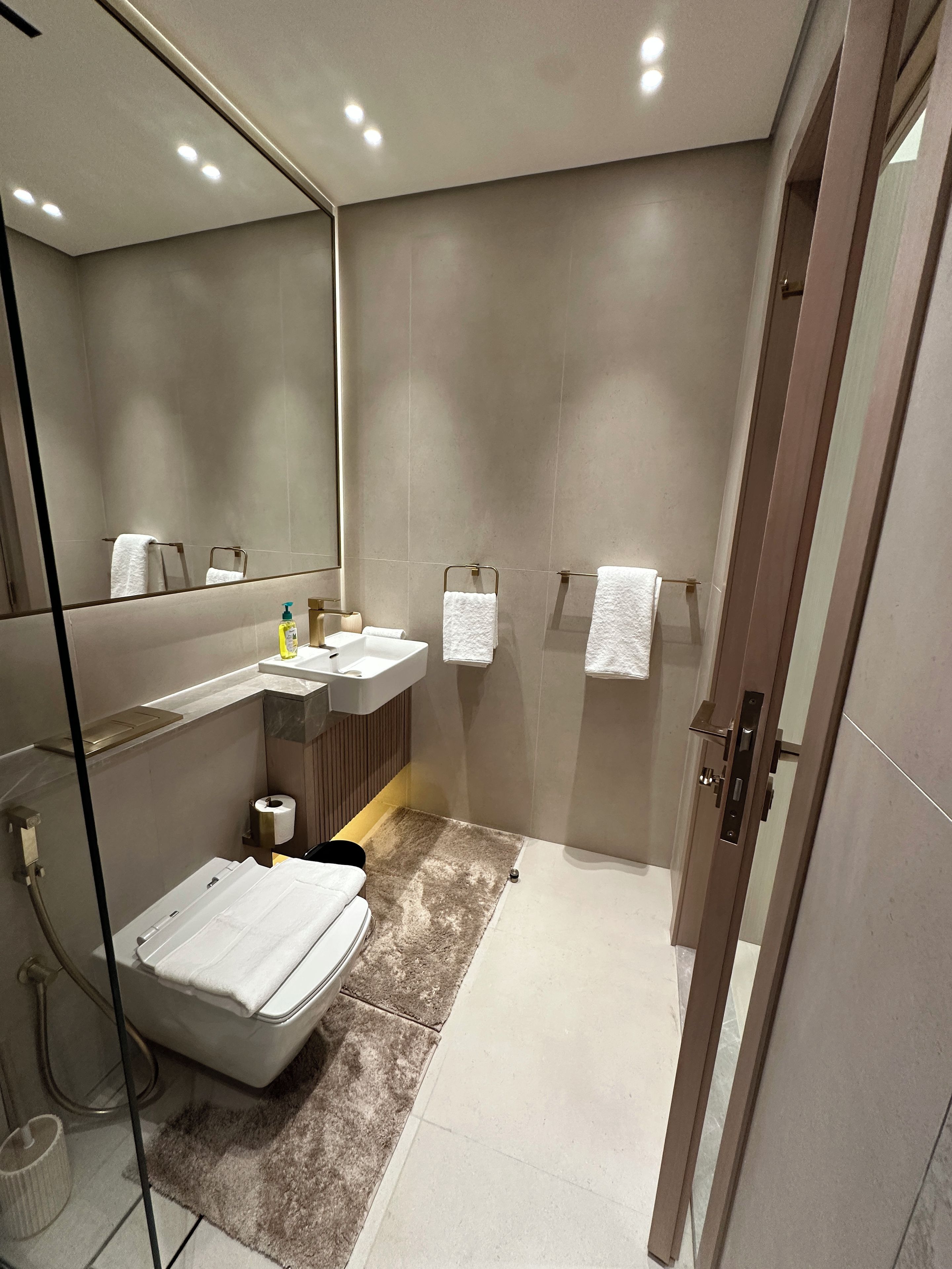 A modern bathroom with a large mirror, a sink, a toilet, and a shower area.
