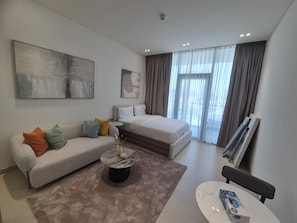 A modern hotel room with a bed, a sofa, a coffee table, and artwork on the walls. - Binghatti Apex (Dubai)