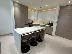 A modern kitchen with a central island, bar stools, and built-in appliances.