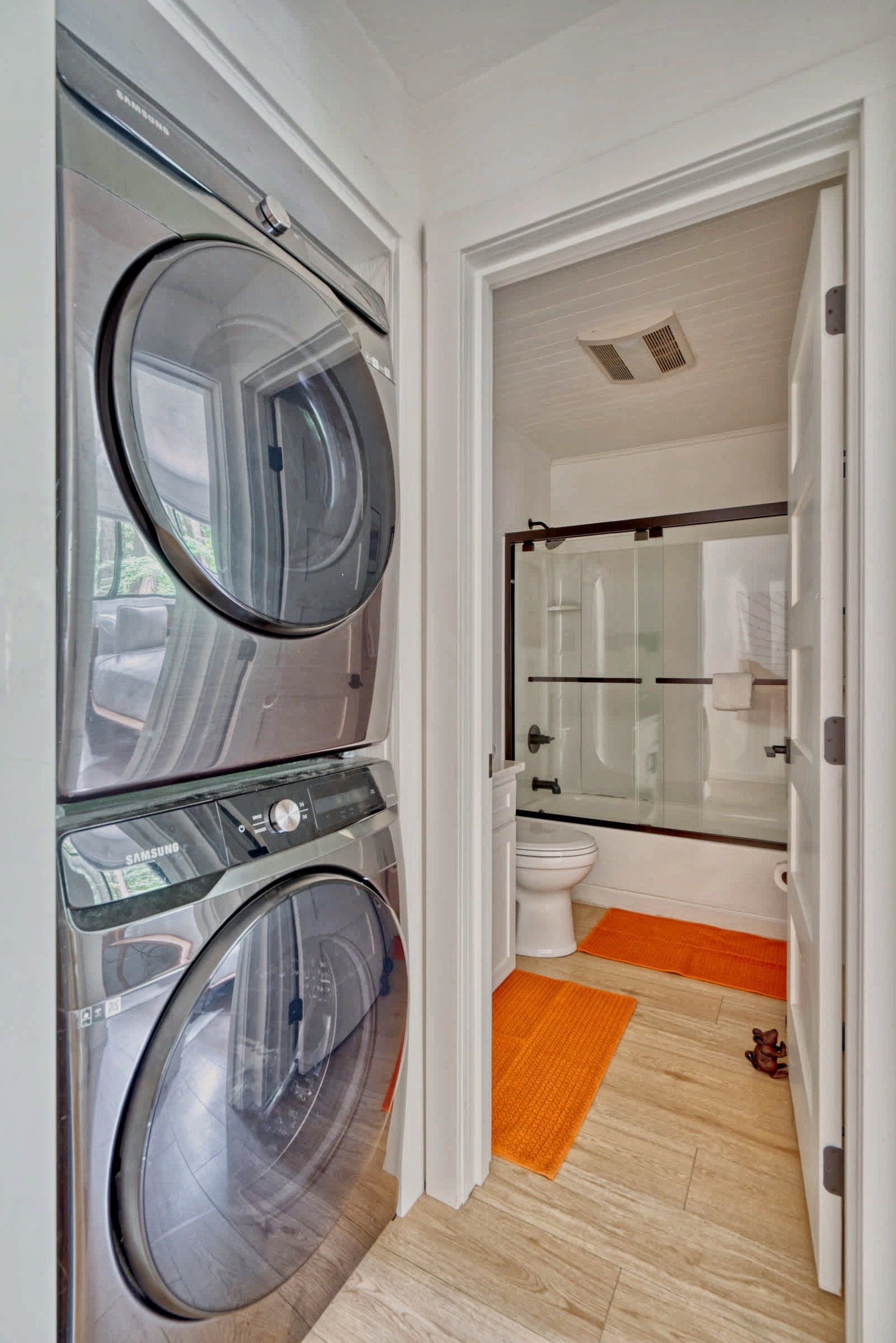 A laundry room with two front-loading washing machines and a glass-enclosed shower area.
