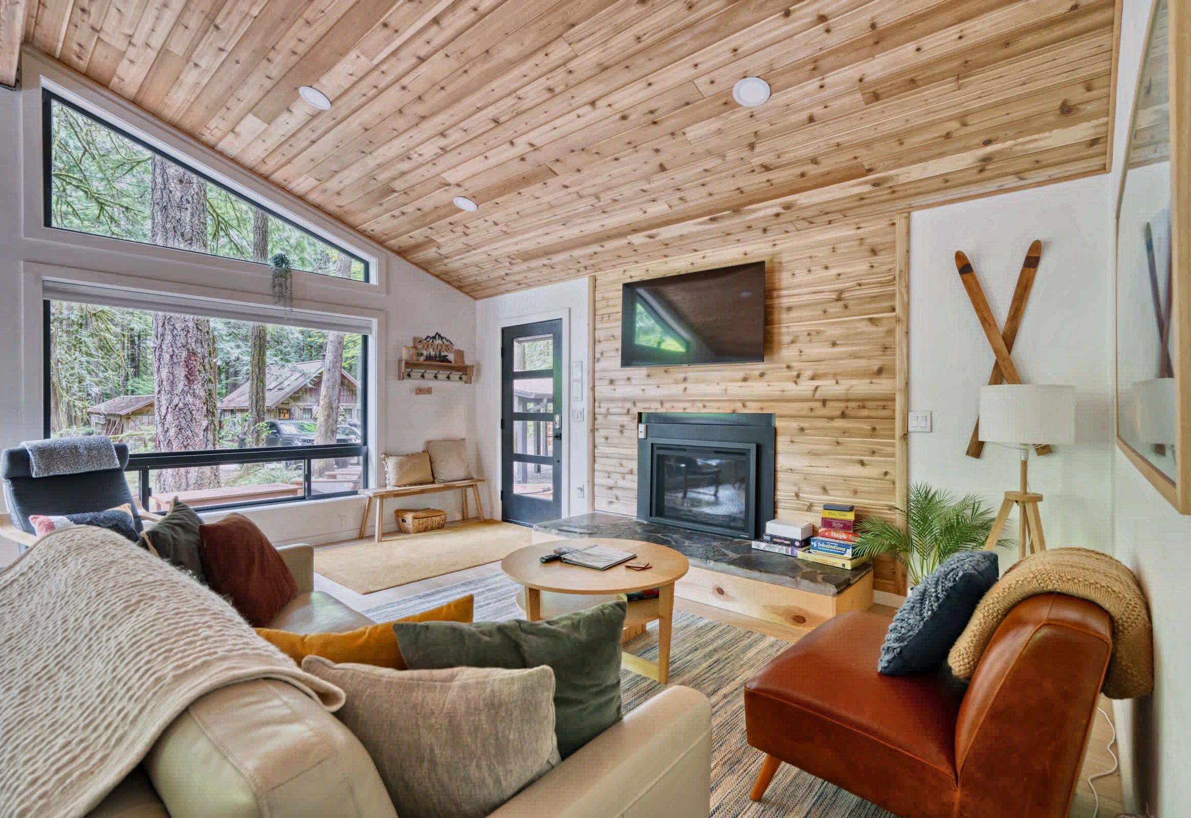 A cozy living room with a fireplace, large windows, and a television.
