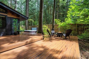 A wooden deck with outdoor furniture, surrounded by a forested area. - Forest Cabin Retreat - Dog Friendly - Hot Tub (Rhododendron)