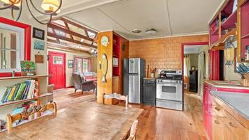 A cozy kitchen with wooden flooring, a dining table, and a red door.