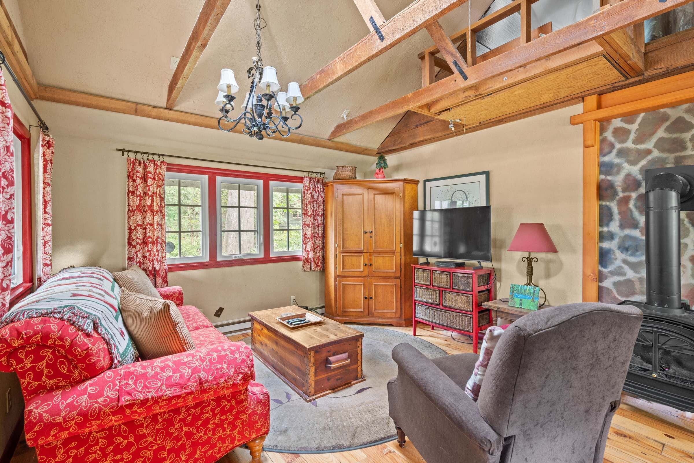 A cozy living room with a sofa, a chair, a wooden coffee table, and a television.