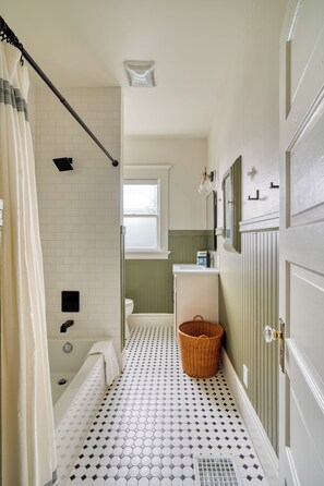 Ein Badezimmer mit Badewanne, Toilette und einem Fenster.