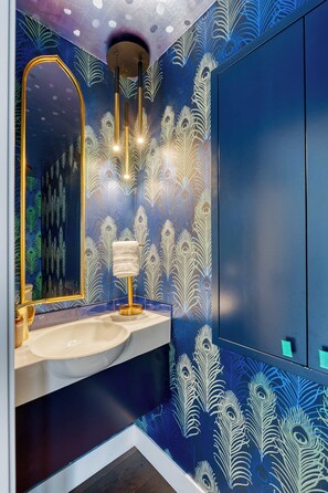 A bathroom with a peacock feather pattern on the walls, a gold-framed mirror, and a white sink. - Aqua Star - Iconic Floating Home, Seen on HGTV (Portland)