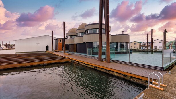 A waterfront property with a dock, a modern building with multiple levels, and a clear view of the water. - Aqua Star - Iconic Floating Home, Seen on HGTV (Portland)