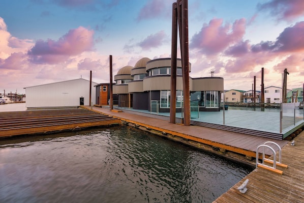 A waterfront property with a dock, a modern building with multiple levels, and a clear view of the water. - Aqua Star - Iconic Floating Home, Seen on HGTV (Portland)