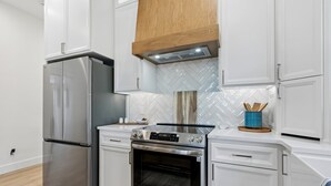 Una cocina moderna con electrodomésticos de acero inoxidable, armarios blancos y salpicadero de baldosas tipo espiga.