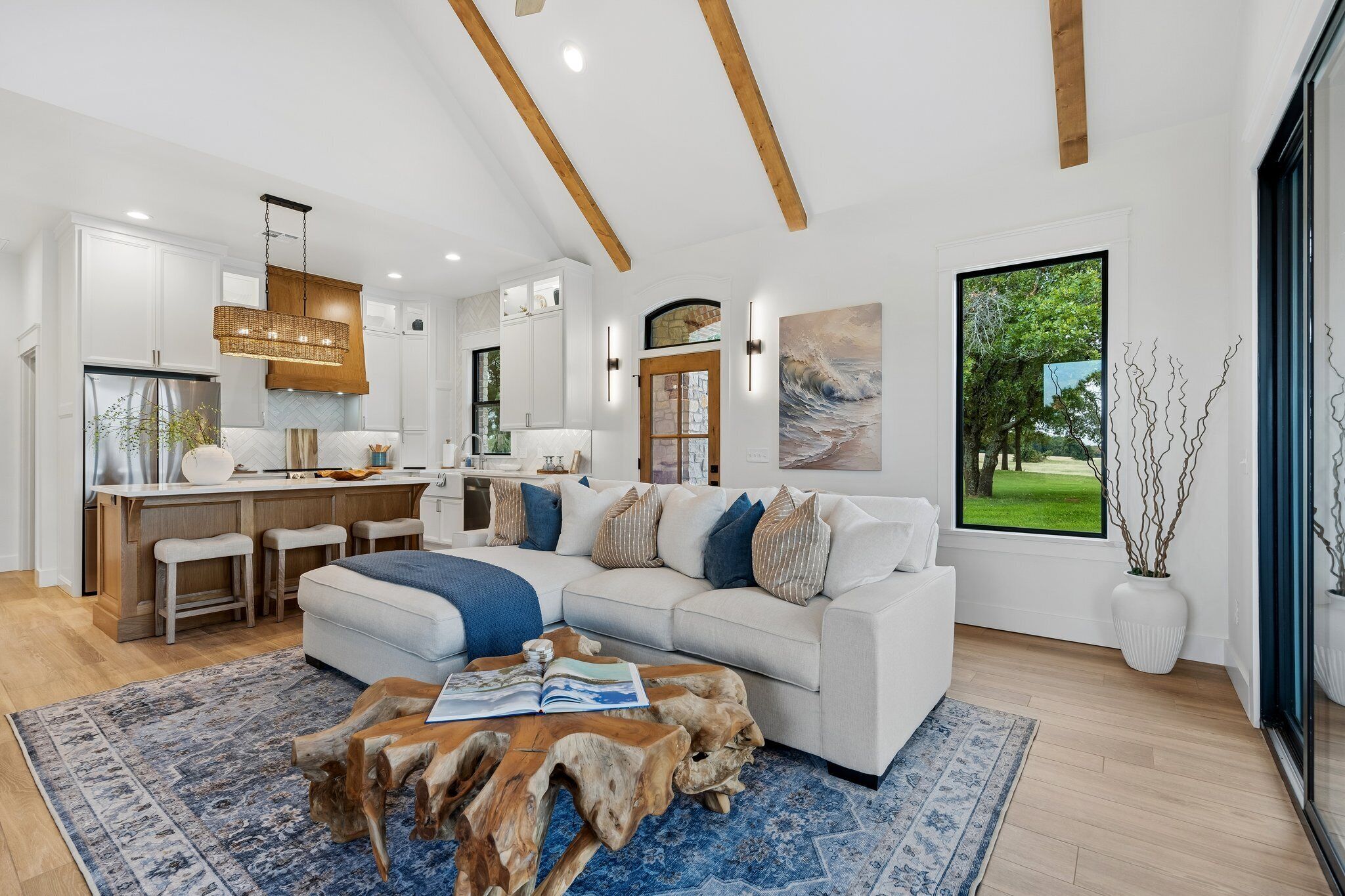 A modern kitchen with white cabinetry, a large island, and a dining area with a white table and chairs.