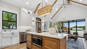 Una cocina moderna con armarios blancos, una isla de madera y un horno empotrado.