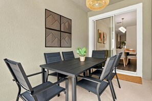 A dining area with a black table and chairs, a potted plant, and a decorative wall piece. - Themed Disney Getaway, Pool & Amazing Location (Kissimmee)