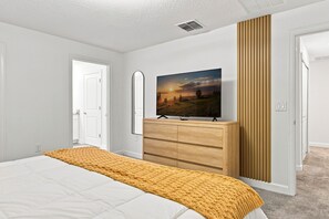 A bedroom with a bed, a dresser, a television, and a mirror. - Chic Disney Retreat with Fun Themed Rooms (Kissimmee)