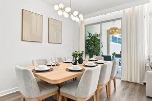 A dining area with a wooden table set for six, surrounded by grey upholstered chairs. - Chic Disney Retreat with Fun Themed Rooms (Kissimmee)
