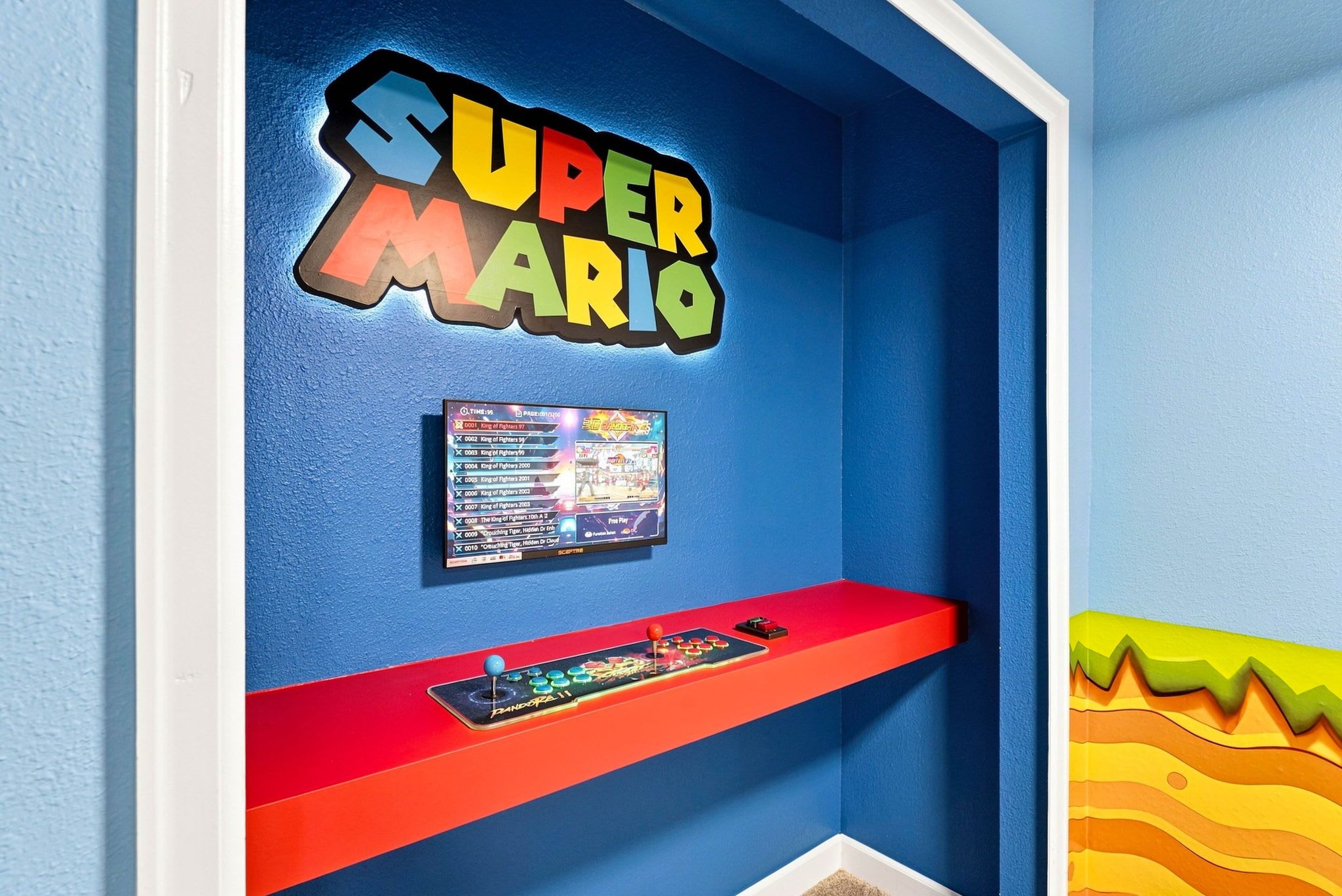 A room with a blue wall, a Super Mario sign, a game console, and a shelf with game cartridges.
