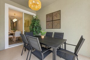 An outdoor dining area with a table and chairs, a potted plant, and a decorative wall panel. - Chic Disney Retreat with Fun Themed Rooms (Kissimmee)