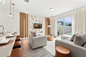 A modern living room with a sofa, armchairs, a coffee table, and a dining area with a table and chairs. - Chic Disney Escape, Themed Rooms & Private Pool (Four Corners)