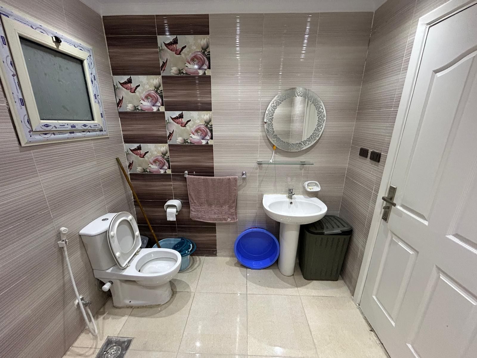 Un baño con inodoro, bidé, lavamanos, espejo y paredes con azulejos.