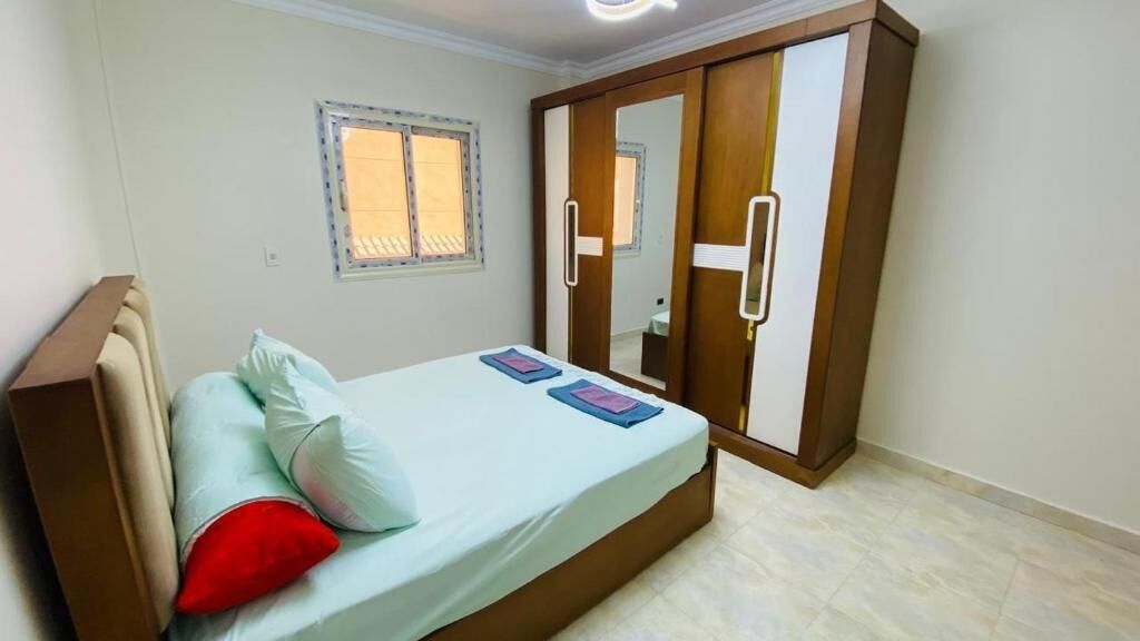 Quarto com cama, guarda-roupa, janela e espelho.