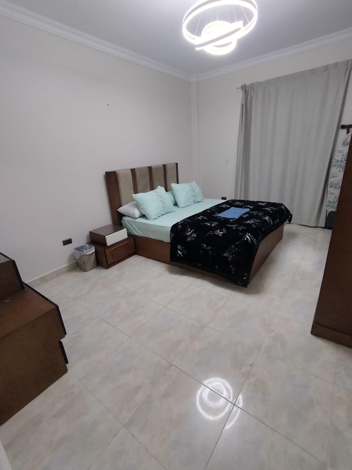 Ein Schlafzimmer mit einem Bett, Nachttischen, einer Treppe und einem Mülleimer.