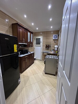 Cozinha equipada com geladeira, fogão, micro-ondas e armários.