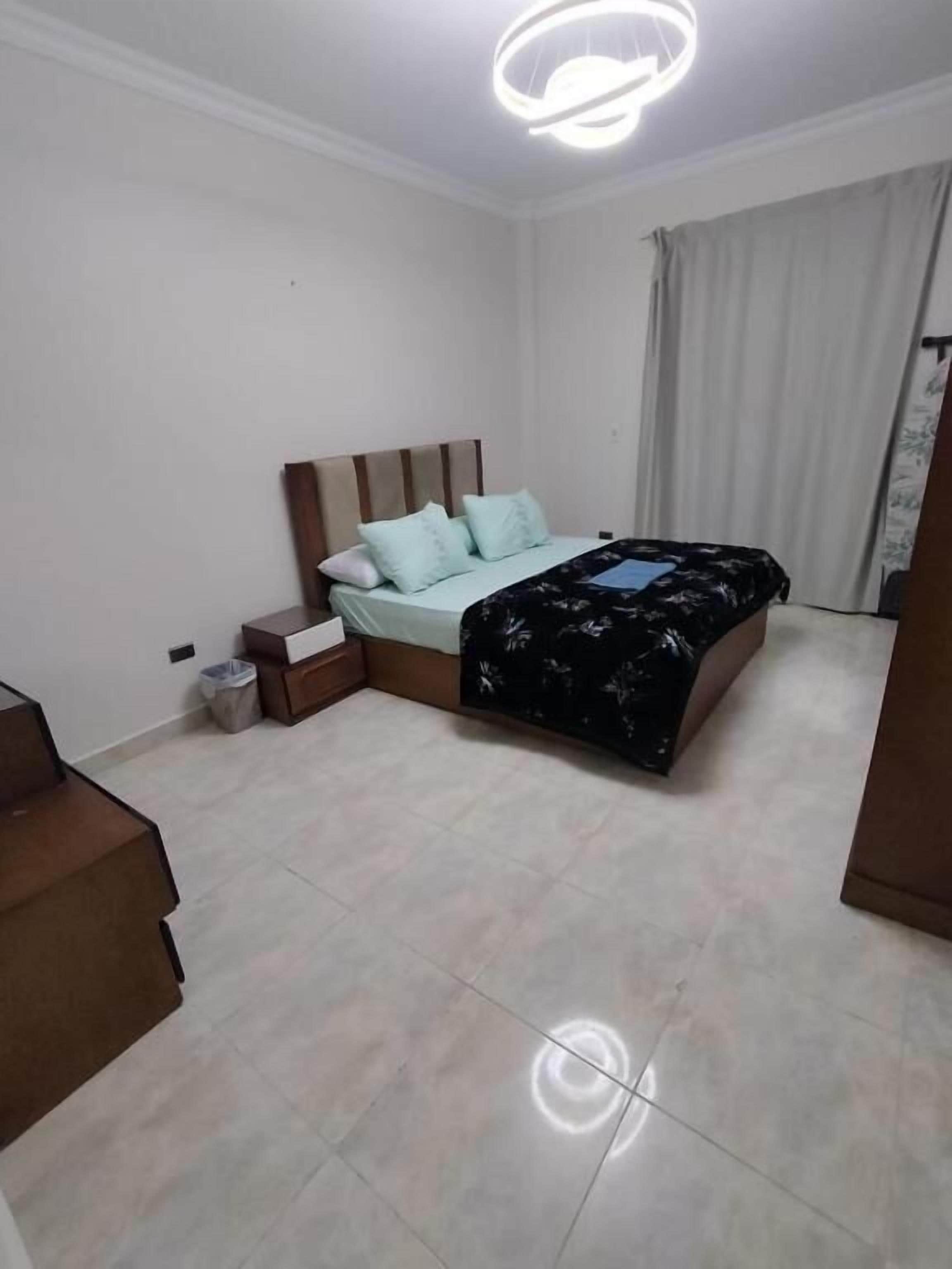 Ein Schlafzimmer mit Bett, Nachttisch, Mülleimer und einer Treppe.