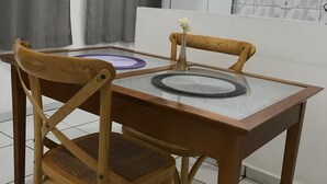 Ein Essbereich mit einem Glastisch, zwei Holzstühlen und einer kleinen Vase mit einer Blume.