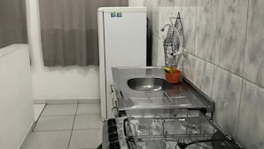 Eine kleine Küche mit Gaskochfeld, Spüle und einem weißen Kühlschrank.