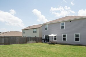 A residential area with two houses, a wooden fence, and a grassy yard.