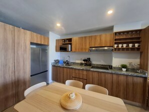 A modern kitchen with wooden cabinets, stainless steel appliances, and a marble countertop. - Nuevo Vallarta apartment with pool (Las Jarretaderas)