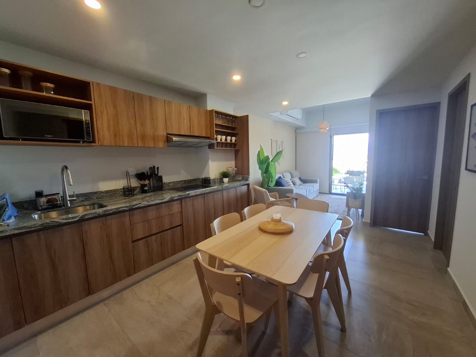 A modern kitchen with wooden cabinets, a granite countertop, and a dining area with a wooden table and chairs.