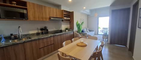 A modern kitchen with wooden cabinets, a granite countertop, and a dining area with a wooden table and chairs.