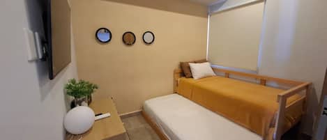 A compact bedroom with a bed, bedside table, and a wall-mounted air conditioner.