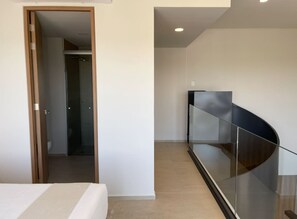 Ein modernes Hotelzimmer mit einem Bett, einer Glastrennwand und Blick auf den Flur.