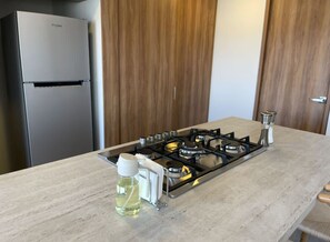 Eine Küche mit einem Edelstahl-Kühlschrank, einem Gasherd und einer Ölflasche auf der Arbeitsfläche.