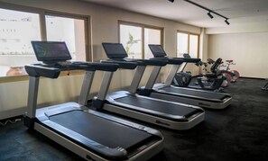 Four treadmills aligned in a row with a stationary bike and elliptical machine in the background. - Zapopan apartment with pool and gym (Zapopan)