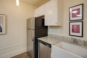 A kitchen with white cabinets, a stainless steel refrigerator, a dishwasher, and a granite countertop. - Historic Downtown Florence | Near Shops & Dining (Florence)
