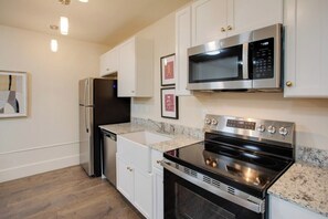 A modern kitchen with white cabinets, a stainless steel refrigerator, a microwave, and an oven. - Historic Downtown Florence | Near Shops & Dining (Florence)