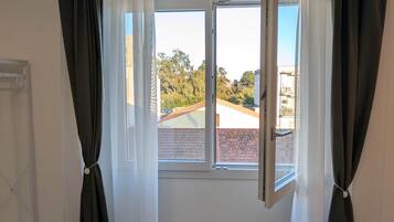 A room with a large window, white walls, and a tiled floor.