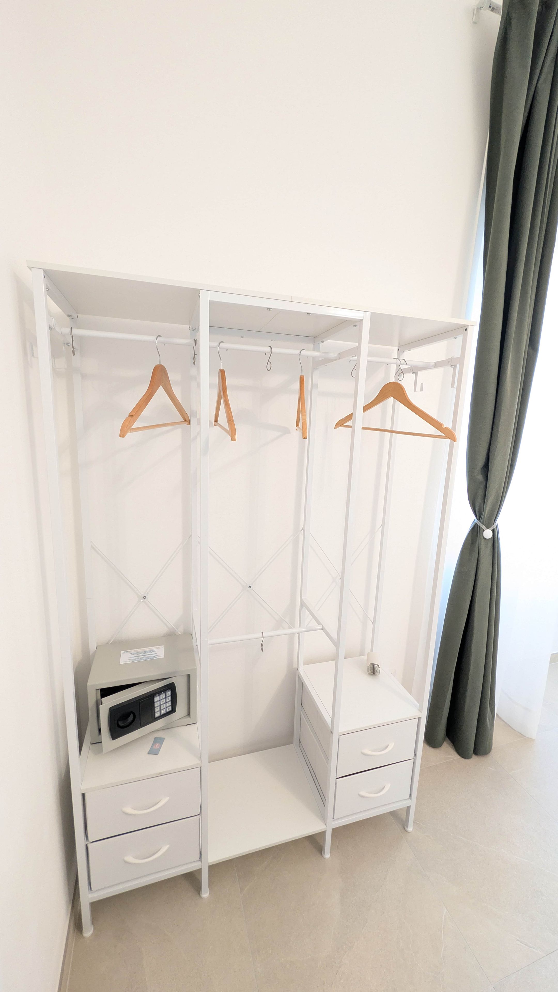 A white wardrobe with multiple compartments and wooden hangers.