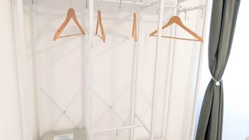 A white wardrobe with multiple compartments and wooden hangers.