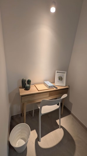 A small, well-lit room with a wooden desk, a white chair, a framed picture, and a cactus on the desk. - Figarolo - Camera Matrimoniale Premium (Olbia)